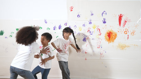 Playful children playing and running with colorful stained hand in front of white background. Funny happy multicultural students enjoy attending in art lesson. Creative activity concept. Erudition.の写真素材
