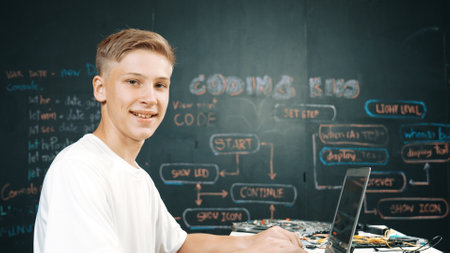 Caucasian boy coding and programing system while looking at laptop screen and camera with confident....