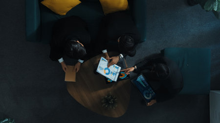 Top down aerial view of professional business man handed out business document to investor while manager placed tablet display financial statistic graph on table and listen presentation. Directorate.の写真素材