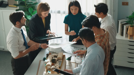 Top down view of manager pointing at house model and explain building design. Aerial view of...