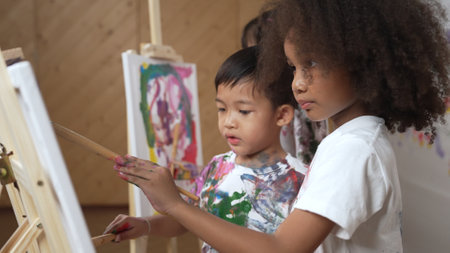 Happy creative african girl painted or draw canvas together with asian boy. Group of playful student create funny painting or artwork painted by watercolor. Creativity activity concept. Erudition.の写真素材
