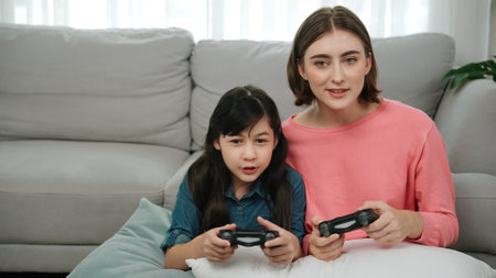 Caucasian mom and daughter sitting and playing game at living room. Happy mother spend time together...