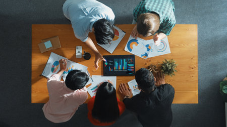 Top down aerial view of smart business people analyze data together at meeting. Group of business team working together and looking at financial chart at tablet placed on meeting table. Convocation.の写真素材