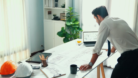 Smart engineer standing and writing idea at blueprint and laptop. Closeup of architect hands...
