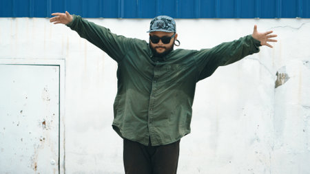 Hipster dancing b-boy foot step at street with blue wall. Asian break dancer practice street dance while stretch arms. Hip hop choreographer perform energetic dance. Outdoor sport 2024. Endeavor.の写真素材