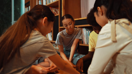 Group of diverse children sitting in circle while reading a book at library. Highschool girl sharing...