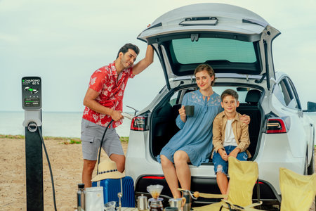 Family vacation trip traveling by the beach with electric car, happy family recharge EV car, enjoying outdoor camping coffee. Seascape travel and eco-friendly car for clean environment. Perpetualの写真素材