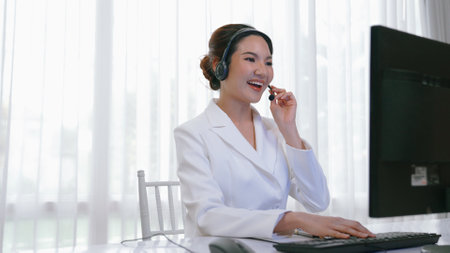 Businesswoman wearing vivancy headset working in office to support remote customer or colleague. Call center, telemarketing, customer support agent provide service on telephone video conference callの写真素材