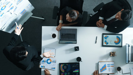 Top view of project manager pointing at board while present marketing plan to investor. Skilled business man planning financial strategy with group of business people at meeting table. Directorate.の写真素材