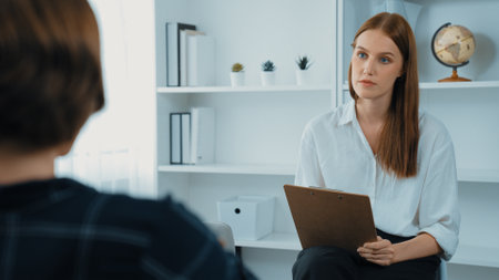 Happy patient and psychologist exchanging mental health conversation in clinic with positive emotion while explaining prim successful work and life to psychologist at psychologist clinic officeの写真素材
