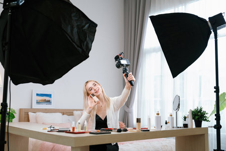 Young woman making beauty and cosmetic tutorial video content for social media. Beauty blogger smiles to camera while showing how to apply beauty skincare to audience or followers. Blitheの写真素材