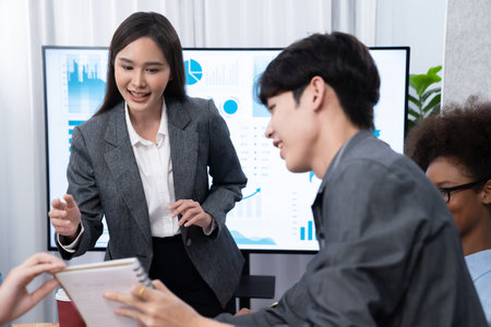 Young asian businesswoman presenting data analysis dashboard on TV screen in modern meeting. Business presentation with group of business people in conference room. Concordの写真素材