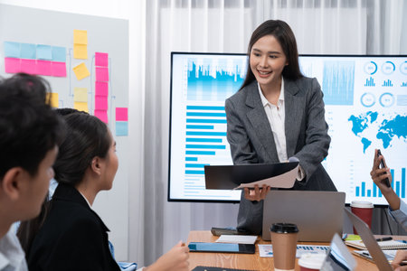 Young asian businesswoman presenting data analysis dashboard on TV screen in modern meeting....
