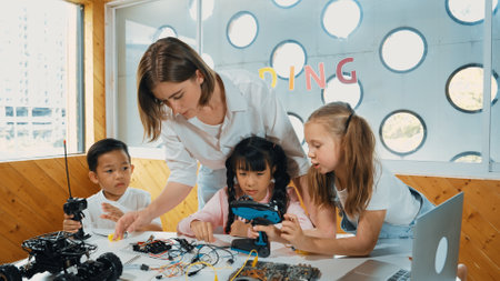 Teacher looking at children while diverse student looking at screen. Children excited in...