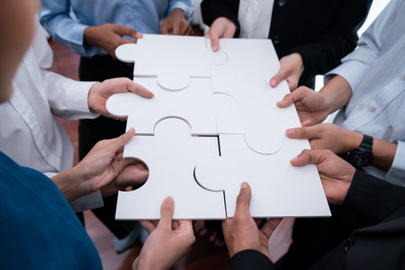 Diverse corporate officer workers collaborate in office, connecting puzzle pieces to represent partnership and teamwork. Unity and synergy in business concept by merging jigsaw puzzle. Concordの写真素材