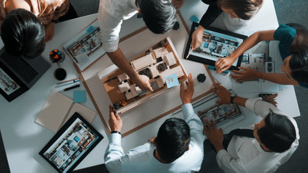 Top down view of manager pointing at house model and explain building design. Aerial view of...