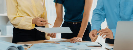 Architect team discuss about blueprint design at modern meeting room while her coworker working on...