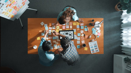 Time lapse of creative designer working together brainstorming idea by using sticky notes at meeting table with color palettes. Aerial view of smart team choosing icon graphic from tablet. Symposium.の写真素材