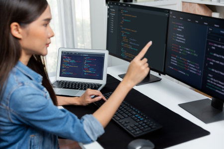 Young Asian girl of IT developer pointing online information on pc with coding program data...