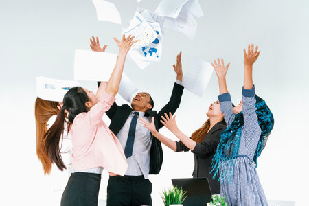 Smiling business people having fun by throwing papers in the air celebrating business success in the modern office. Happy workplace and casual career company concept. udsの写真素材