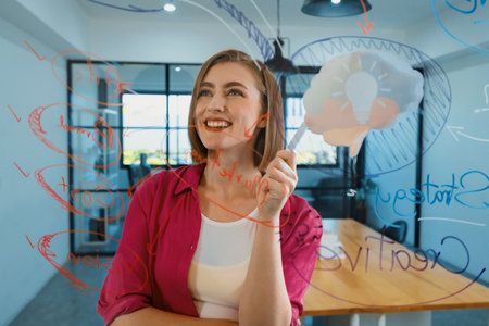 Closeup of attractive smart caucasian businesswoman brainstorms and planing marketing idea by using mind map and colorful sticker on glass board. Creative start up business concept. Immaculate.の写真素材