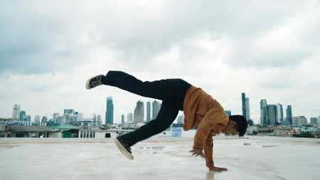 Motion shot of B-boy dance performance by professional street dancer at rooftop with sky scrapper, city view. Attractive asian hipster show energetic footstep. Outdoor sport 2024. Endeavor.の写真素材