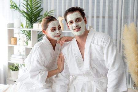 Blissful couple in bathrobe with facial cream mask enjoying serene ambiance of spa salon resort or hotel during holiday. Pampering face spa and skincare treatment with essence relaxation. Quiescentの写真素材