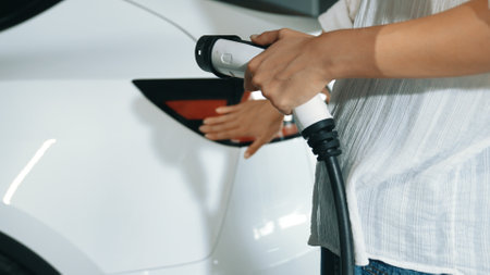 Young motion woman travel with EV electric car to shopping center parking lot charging station in downtown city sustainability lifestyle by green clean rechargeable energy of electric vehicle innardsの写真素材