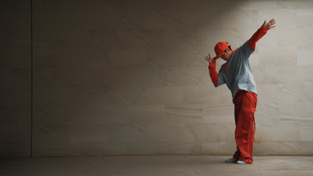 Handsome choreographer practice street dance in gray background. Young attractive b boy dancer perform while wearing stylish cloth. Feeling of lively step. Copy space. Outdoor sport 2024. Sprightly.の写真素材