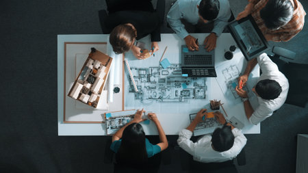 Top aerial view of project manager or civil engineer writing at blueprint and planning building design. Aerial view of architect working together at meeting table with document placed. Alimentation.の写真素材