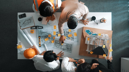 Top down view of skilled engineer team compare between blueprint and house plan. Aerial view of group of architect or designer discussing and point note to brainstorm about blueprint. Alimentation.の写真素材