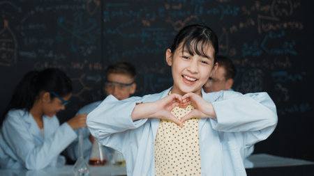 Asian scientist show miniheart to camera while diverse group doing experiment. Young schoolgirl...