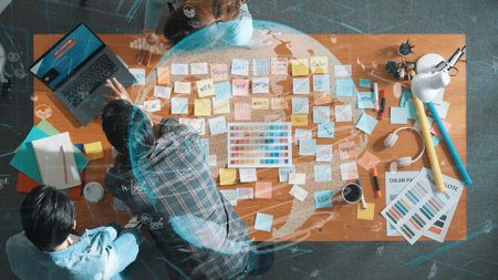Top down view of business team with casual outfit looking laptop screen and sharing idea. Aerial...