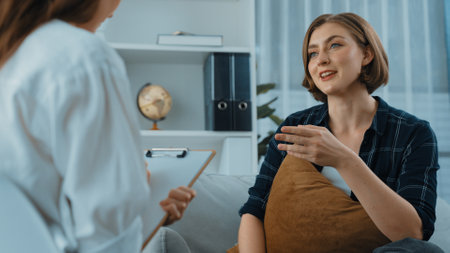 Happy patient and psychologist exchanging mental health conversation in clinic with positive emotion while explaining prim successful work and life to psychologist at psychologist clinic officeの写真素材