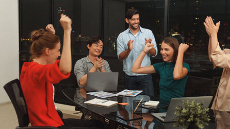 Businesspeople putting hands together and clapping hands to celebrate successful project at modern...