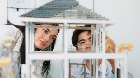 Close up of cooperative professional engineer working together to measuring house model structure....