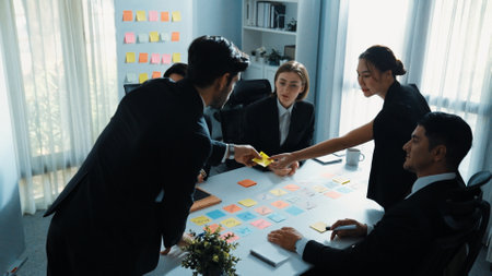 Top view of smart businessman putting sticky note on whiteboard while marketing team brainstorm creative idea at meeting room. Leader explain startup project to group of diverse investor. Directorate.の写真素材