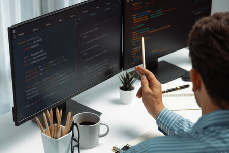 IT developer man pointing information on laptop screen at back side view, thinking program update...