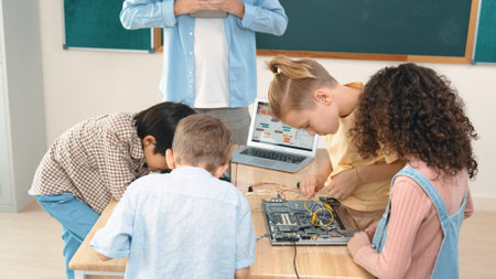 Group of diverse student working together on main board with laptop screen display engineering prompt written while teacher hold tablet and explain online software at STEM technology class. Pedagogy.の写真素材