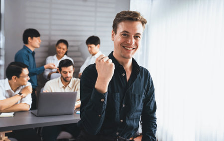 Confidence and happy smiling businessman portrait with background of his colleague and business team working in office. Office worker teamwork and positive workplace concept. Prudentの写真素材