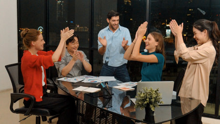 Businesspeople putting hands together and clapping hands to celebrate successful project at modern...