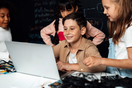 In classroom student in STEM class learning about coding robotics car. Brown shirt Schoolboy and white bib schoolgirl watching laptop and discussing. Other schoolgirls playing around funny. Erudition.の写真素材
