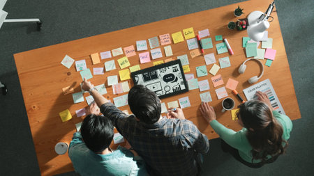 Time lapse of creative designer working together brainstorming idea by using sticky notes at meeting table with color palettes. Aerial view of smart team choosing icon graphic from tablet. Symposium.の写真素材