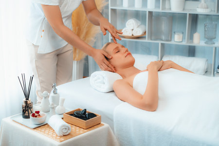 Caucasian woman enjoying relaxing anti-stress head massage and pampering facial beauty skin recreation leisure in dayspa modern light ambient at luxury resort or hotel spa salon. Quiescentの写真素材