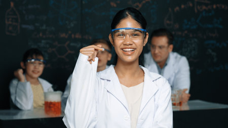 Girl looking at camera with arm folded while people doing experiment at laboratory. Cute student...