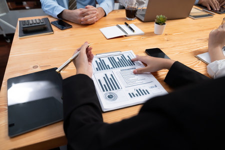 Diverse group of business analyst team analyzing financial data report paper on office table. Chart...