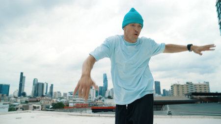 Caucasian B-boy dancer practicing street dancing at rooftop with city urban view. Motion shot of young man performing street dance by moving with hip -hop music. Outdoor sport 2024. Endeavor.の写真素材