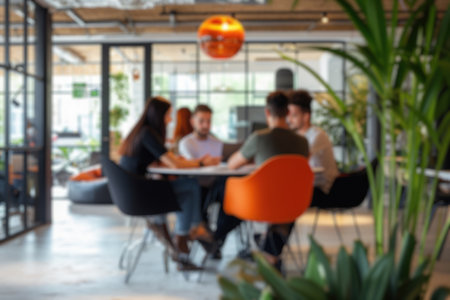 Blurred photo capturing the dynamic atmosphere of a modern open-plan office with people engaged in discussion and work. Resplendent.の写真素材