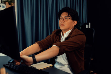 Creative manager working on desk with stretching arm up and down manner with body health ache of strain overwork while searching information report on website on pc at late over night time. Infobahn.の写真素材