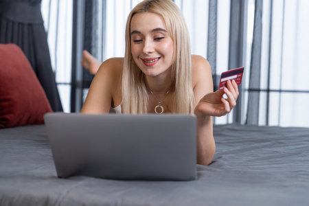 Young woman using laptop with credit card for internet banking, online shopping E commerce by online payment gateway at home office. Modern and convenience online purchasing with debit card. Blitheの写真素材